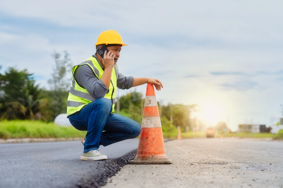 Construction worker checking roadwork progress with phone call