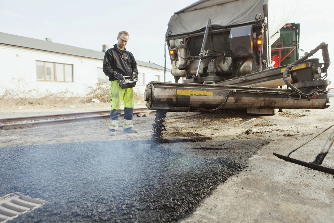 worker paving the road with fresh asphalt